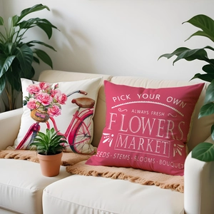 Detail of floral linen pillow covers featuring vintage bicycle and rose patterns on a beige sofa