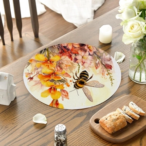 Close-up of circular placemat with floral and bee prints on a rustic wooden table