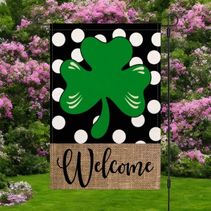 Detail of St. Patrick's clover garden flag with Welcome text hanging on a lawn