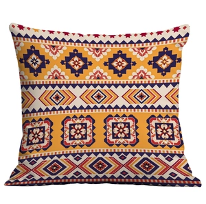 Détail d'une housse de coussin bohème aux motifs géométriques orange et bleu marine