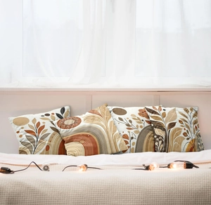 Detail view of four bohemian pillow covers with abstract sunset and leaf designs on a bed
