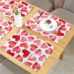 Detailed view of four rectangular placemats with watercolor hearts on a wooden table