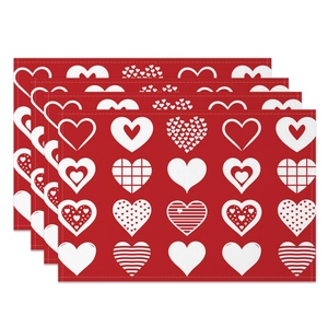 Detail of four red Valentine's Day placemats with white heart patterns and stitched edges