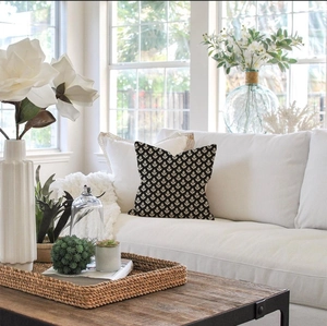 Detail of a square cushion with a black and white floral pattern on a white sofa