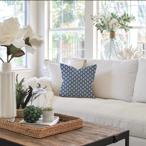 Navy blue floral cushion on a white sofa in a bright modern living room setting