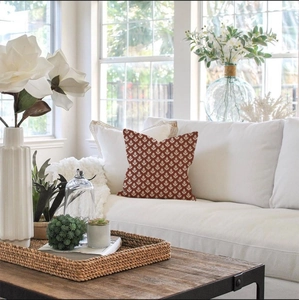 Close-up of square floral pillow cover with terracotta leaf pattern on white sofa