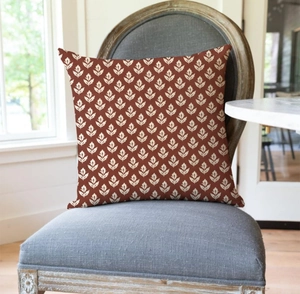Detail of vintage red floral square cushion cover on grey armchair in sunlit room