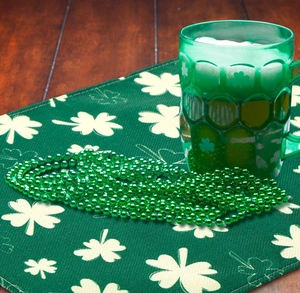 Detail of St. Patrick's Day placemat with green clover beads and a themed drink mug