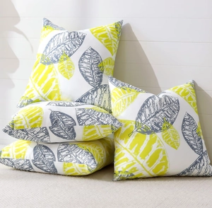 Set of four cushion covers with green leaf patterns displayed on a soft rug