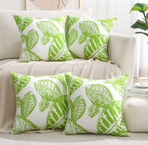 Detail view of four square peach skin pillowcases with green leaf patterns for sofa decor