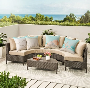 Outdoor curved rattan sofa set with beige cushions and sea-themed waterproof pillows