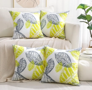 Detailed view of four peach skin pillows with yellow leaf patterns on a white sofa