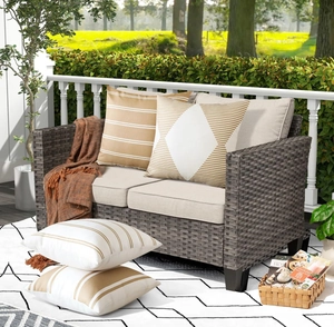Close-up of geometric pattern pillows and throw on outdoor rattan sofa with beige cushions