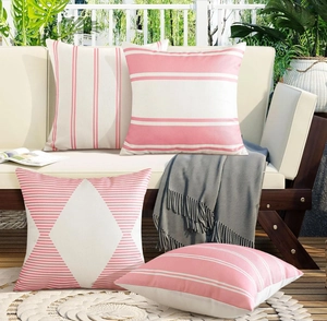 Sofá de madera exterior con cuatro fundas de cojín impermeables geométricas en rosa y blanco
