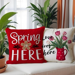 Floral typography throw pillow set in deep red and cream on a white leather sofa