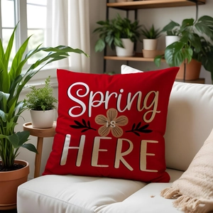 Detailed view of red square pillow with Spring IS HERE print on white fabric sofa