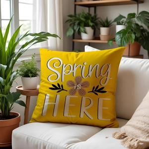 Close-up of yellow linen pillowcase with Spring IS HERE floral print on a white sofa