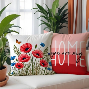 Close-up of floral poppy print and HOME typography cushion covers on a sofa