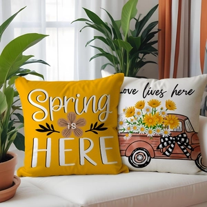 Detail of yellow and beige spring pillow covers with floral truck and typography on sofa