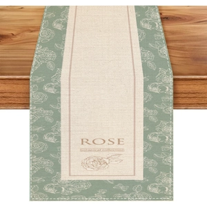 Close-up of linen table runner with botanical rose print and sage green floral borders
