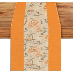 Detail of bohemian floral table runner showing orange borders and linen texture on wood