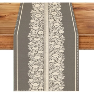 Macro detail of taupe table runner with white floral lace pattern on wooden table