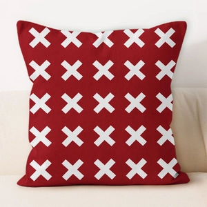 Close-up of deep red pillow cover with white geometric X-patterns on a light sofa