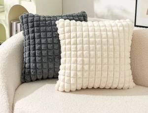 Detail of square faux rabbit fur pillow covers in dark gray and cream with grid texture