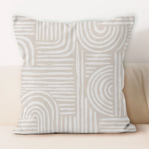 Detail of cream geometric pillow cover with white hand-drawn lines on a soft couch