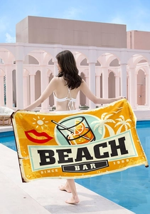 Detail view of microfiber beach towel with vintage Beach Bar print and orange sunset graphics