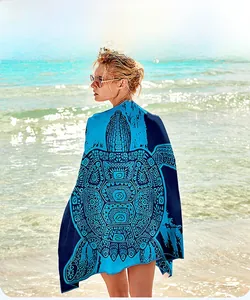 Detail view of microfiber beach towel featuring a blue sea turtle print in beach setting