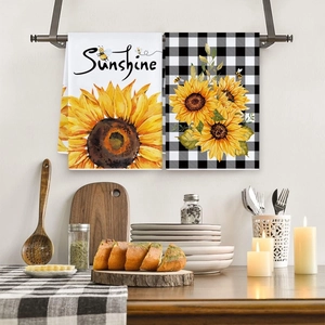 Two-pack kitchen towels with sunflower prints and plaid patterns on a metal rack
