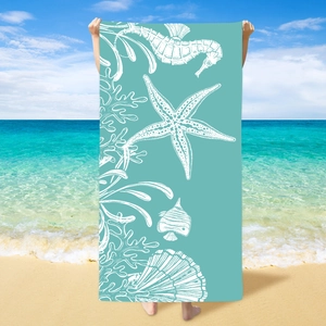 Microfiber beach towel with sea life prints on sandy beach with blue ocean