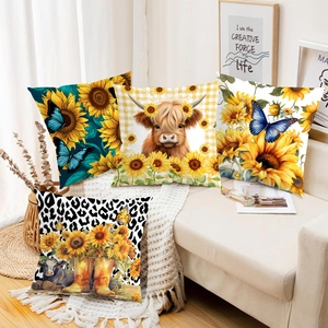 Detail von vier Kissenbezügen mit Sonnenblumen und Highland-Rindern auf dem Sofa