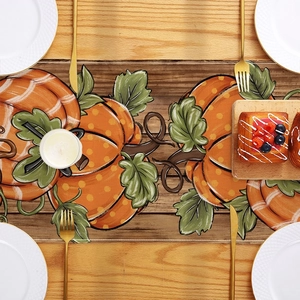 Close-up of harvest pumpkin table runner with rustic wood background and dinnerware