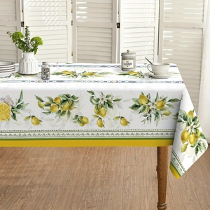 Detailed view of tablecloth with vivid lemon and green leaf patterns on white fabric