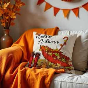 Detail of Hello Autumn pillow cover with boots and umbrella on a cozy sofa