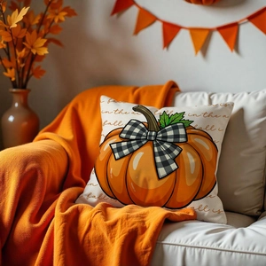 Close-up of harvest pumpkin pillow cover with plaid bow on a cozy autumn sofa