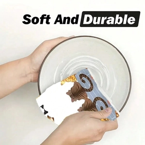 Soft and durable cat print dish towel cleaning a white ceramic plate in a kitchen setting