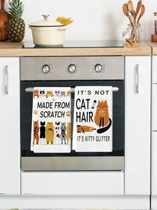 Detail of white microfiber kitchen towels with cartoon cat prints hanging on oven handle