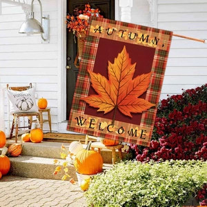 Detail of autumn garden flag featuring orange maple leaf and welcome message on a porch