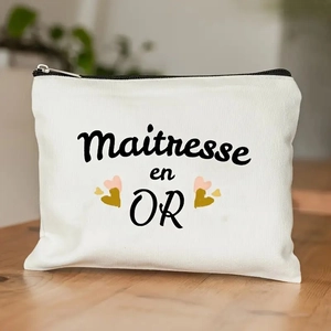 Detail of canvas pouch featuring Maîtresse en OR text and gold heart prints on a desk