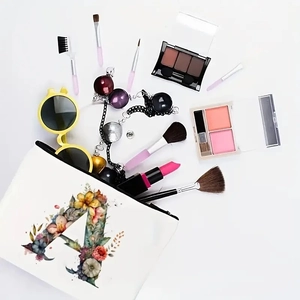 White canvas makeup bag featuring floral letter A design with zipper and cosmetics accessories