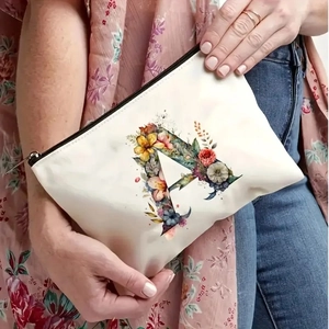 White canvas makeup bag with floral letter A pattern shown with lifestyle model