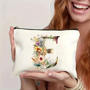 Detail of cream makeup bag featuring floral letter E held by smiling model