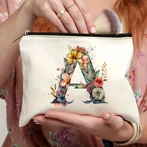Canvas makeup bag with floral letter A print being held by a model in a floral dress