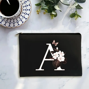 Black fabric makeup bag with letter A and pink floral print on marble background