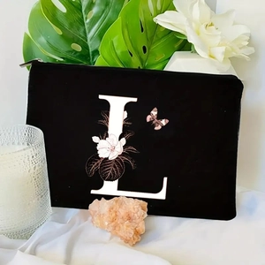 Detail of black velvet makeup bag featuring floral letter L design and metal zipper closure