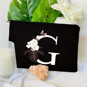 Detail of black velvet makeup bag with floral letter G print and gold zipper close-up