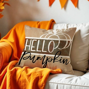 Close-up of autumn pillow cover with pumpkin print and HELLO pumpkin text on a cozy sofa